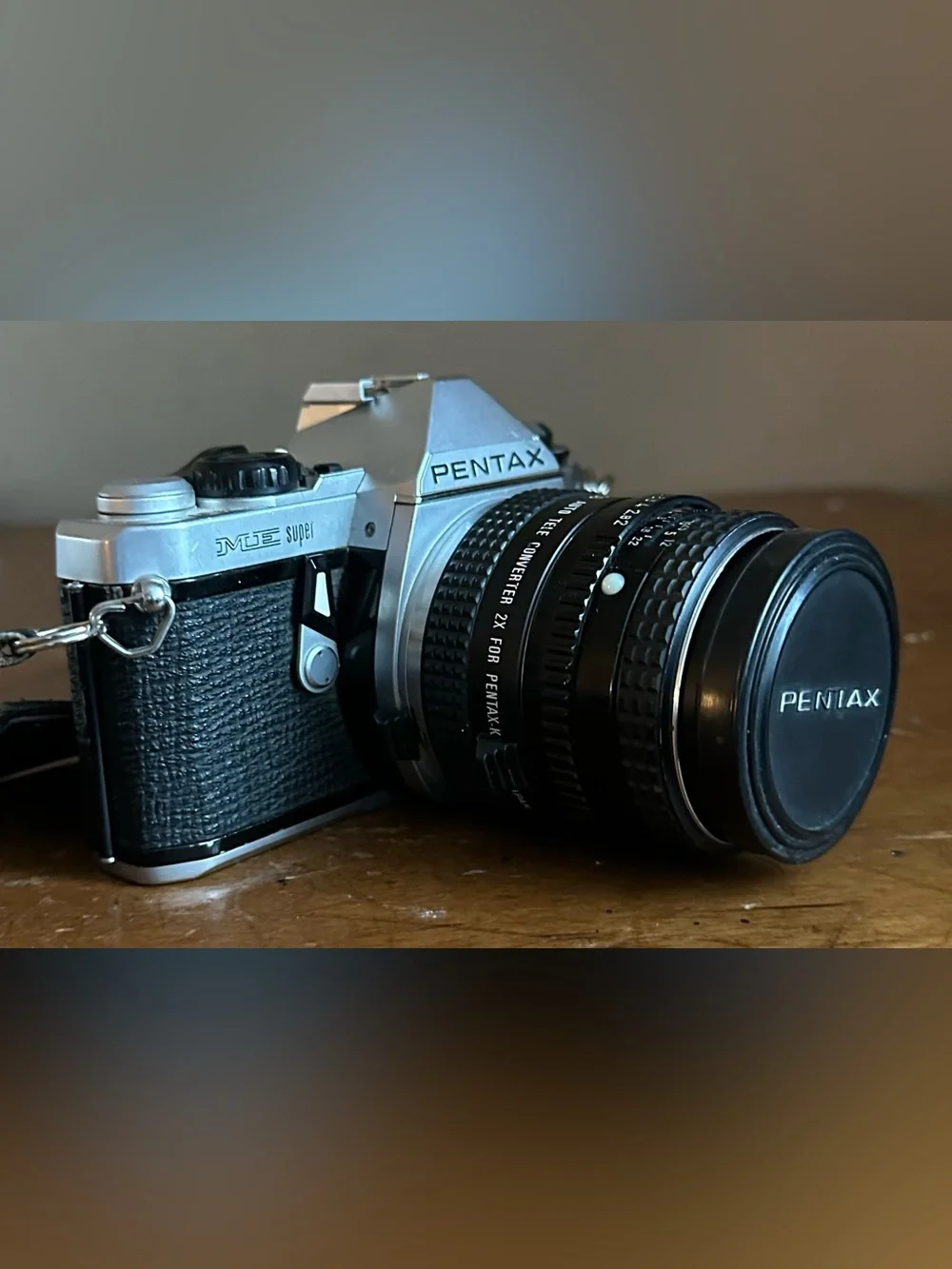 Pentax Silver and Black SLR Camera with Black Lens Cap and Colorful Strap